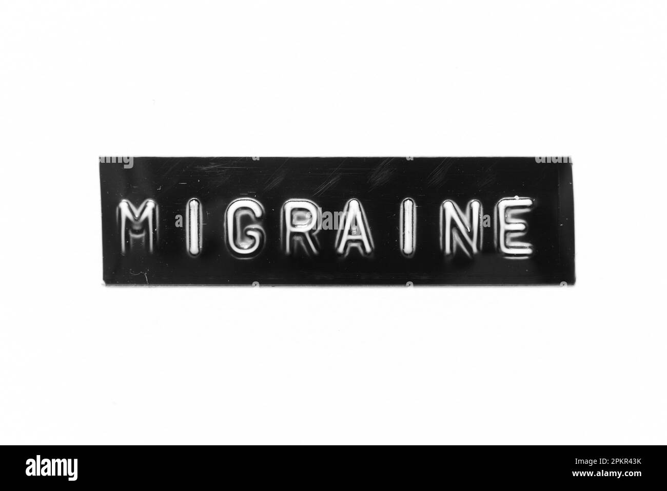 Schwarzes Banner mit geprägtem Buchstaben und dem Wort Migräne auf weißem Papierhintergrund Stockfoto