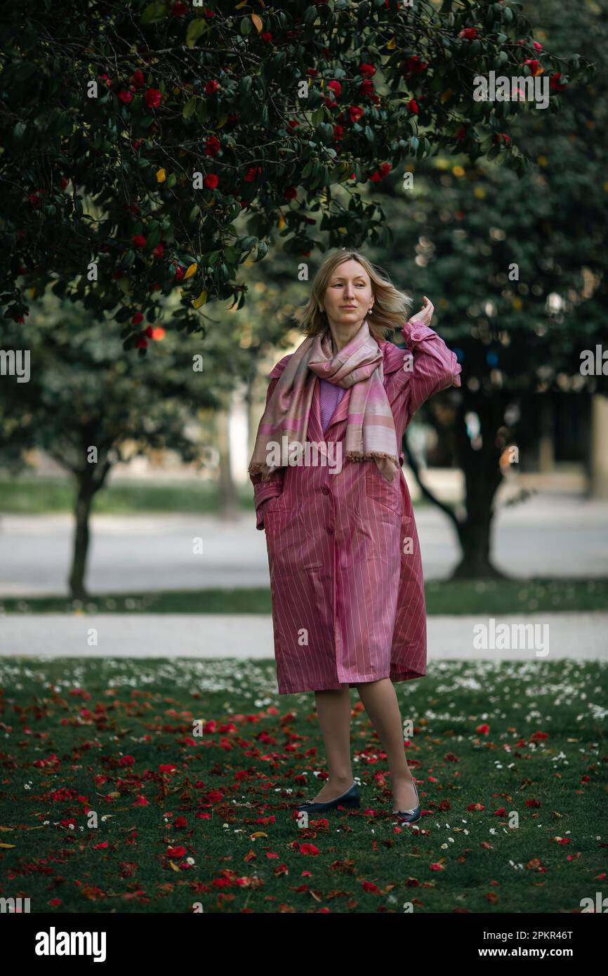 Eine Frau in einem rosa Regenmantel posiert im Park. Stockfoto