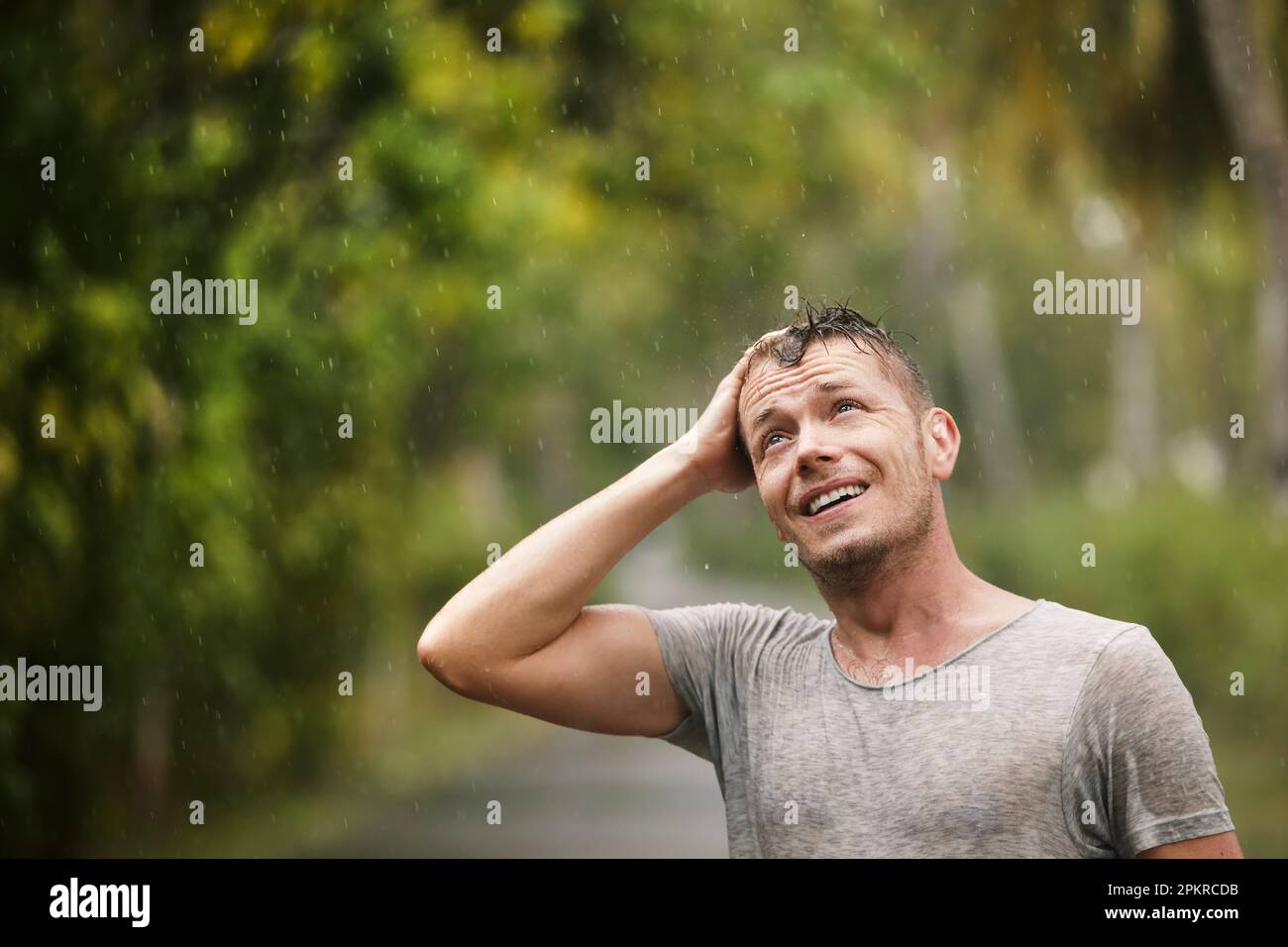 Porträt des Menschen in nasser Kleidung, der starken Regen in der Natur genießt. Themen des Lebens Wasser, Wetter und Umwelt. Stockfoto