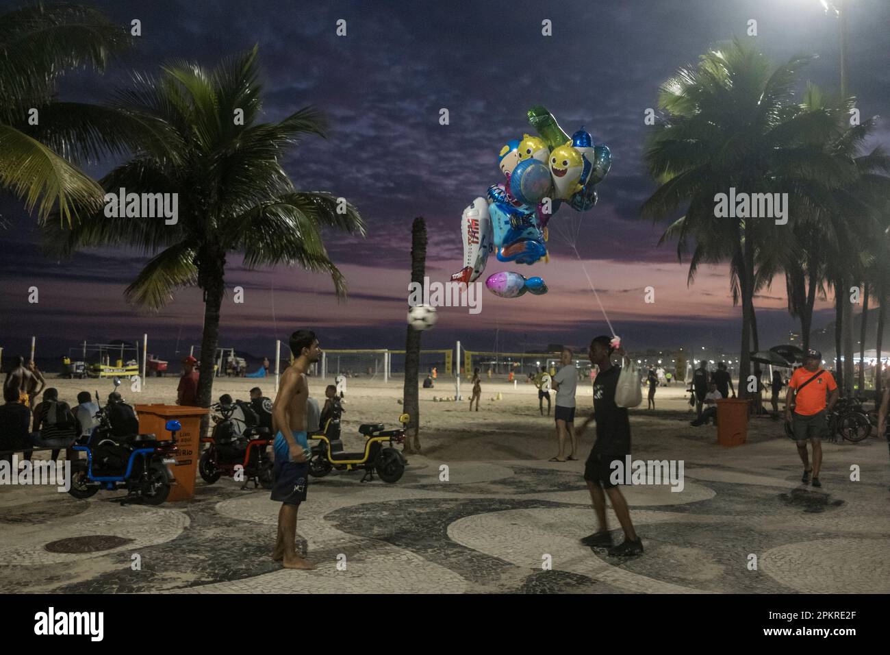 Der Spielzeugballonverkäufer hört für ein paar Minuten auf zu arbeiten, um mit einem Kollegen auf der Copacabana Promenade mit einem Fußball zu spielen. Rio de Janeiro Lifestyle, Brasilien. Stockfoto