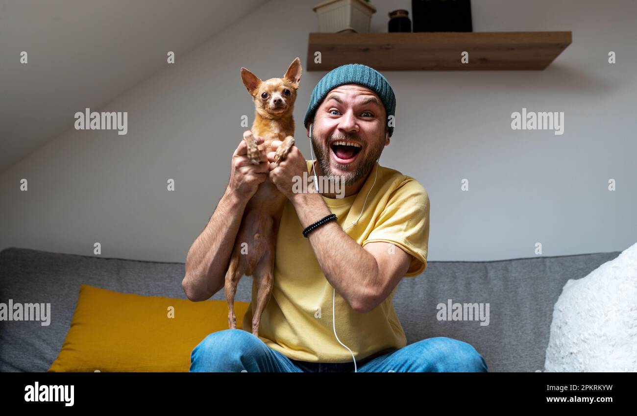 Glücklicher Mann und sein kleiner Hund zusammen zu Hause. Stockfoto