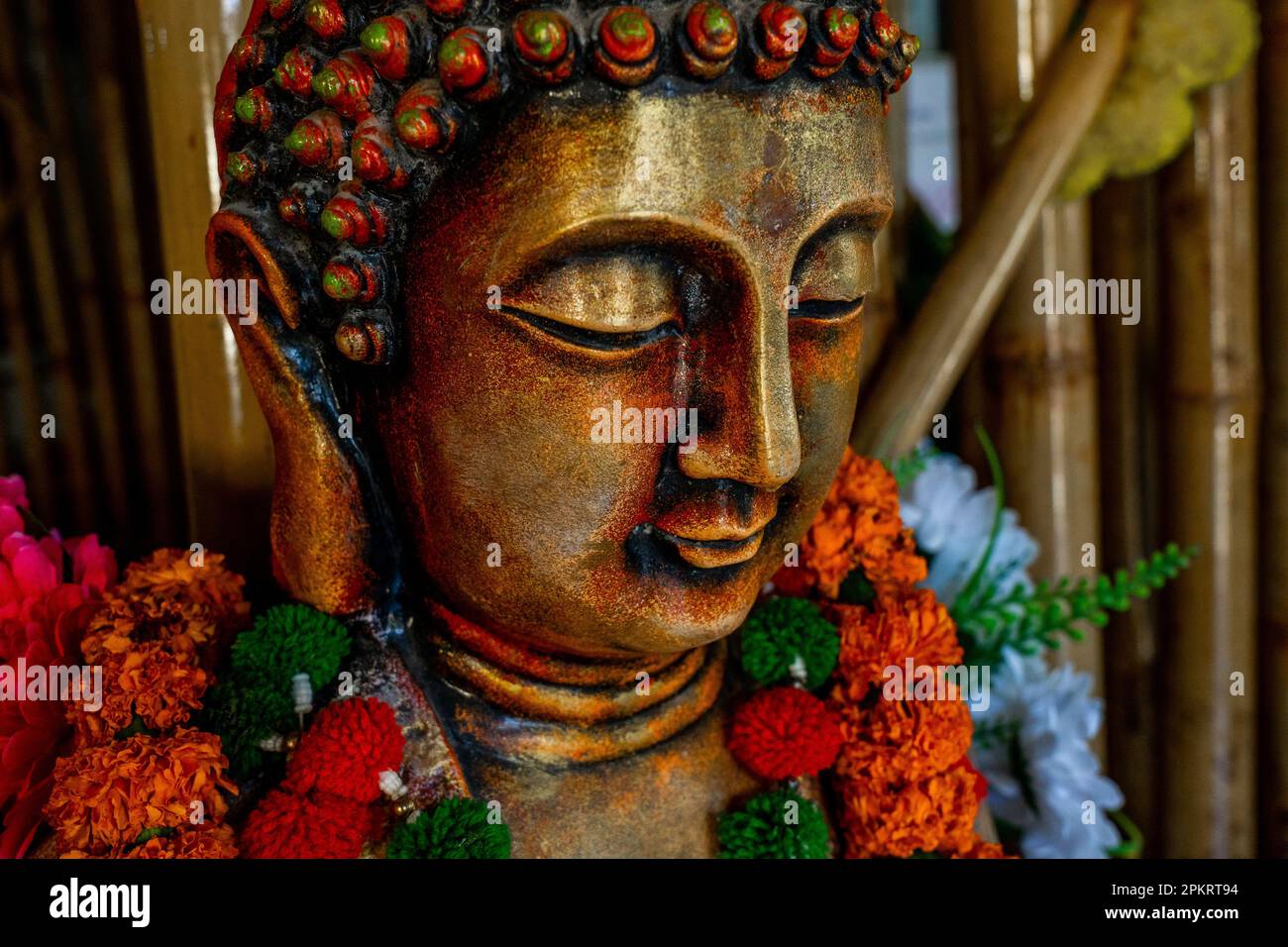 Nahaufnahme der bronzenen buddha-Statue, die in Meditation mit Blumendekorationen für die Festivalzeremonie sitzt. Hochwertiges Foto Stockfoto