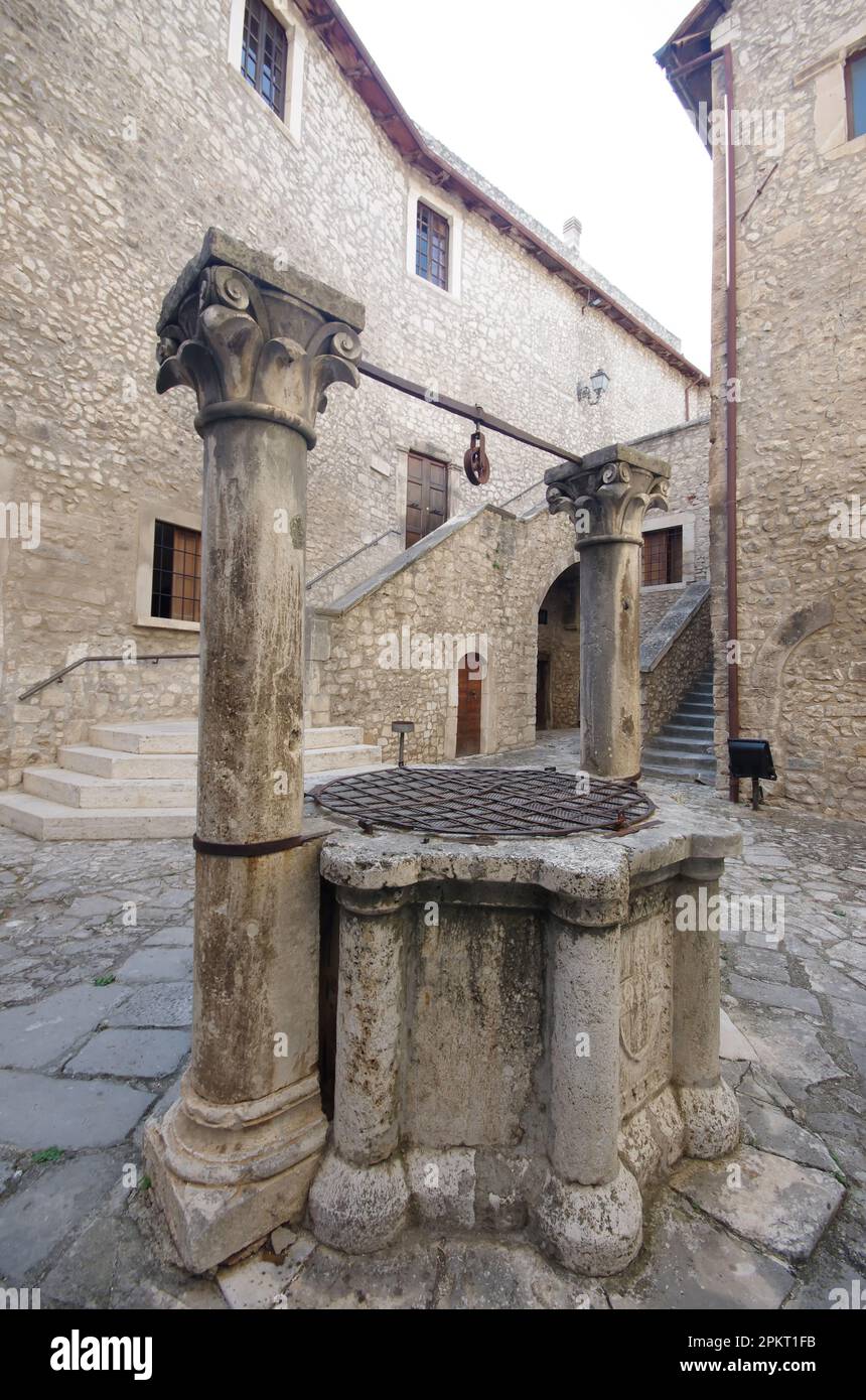 Piccolomini Schloss Capestrano (AQ - Marmorbrunnen aus dem 15. Jahrhundert, flankiert von Säulen mit belaubten Hauptstädten. Stockfoto