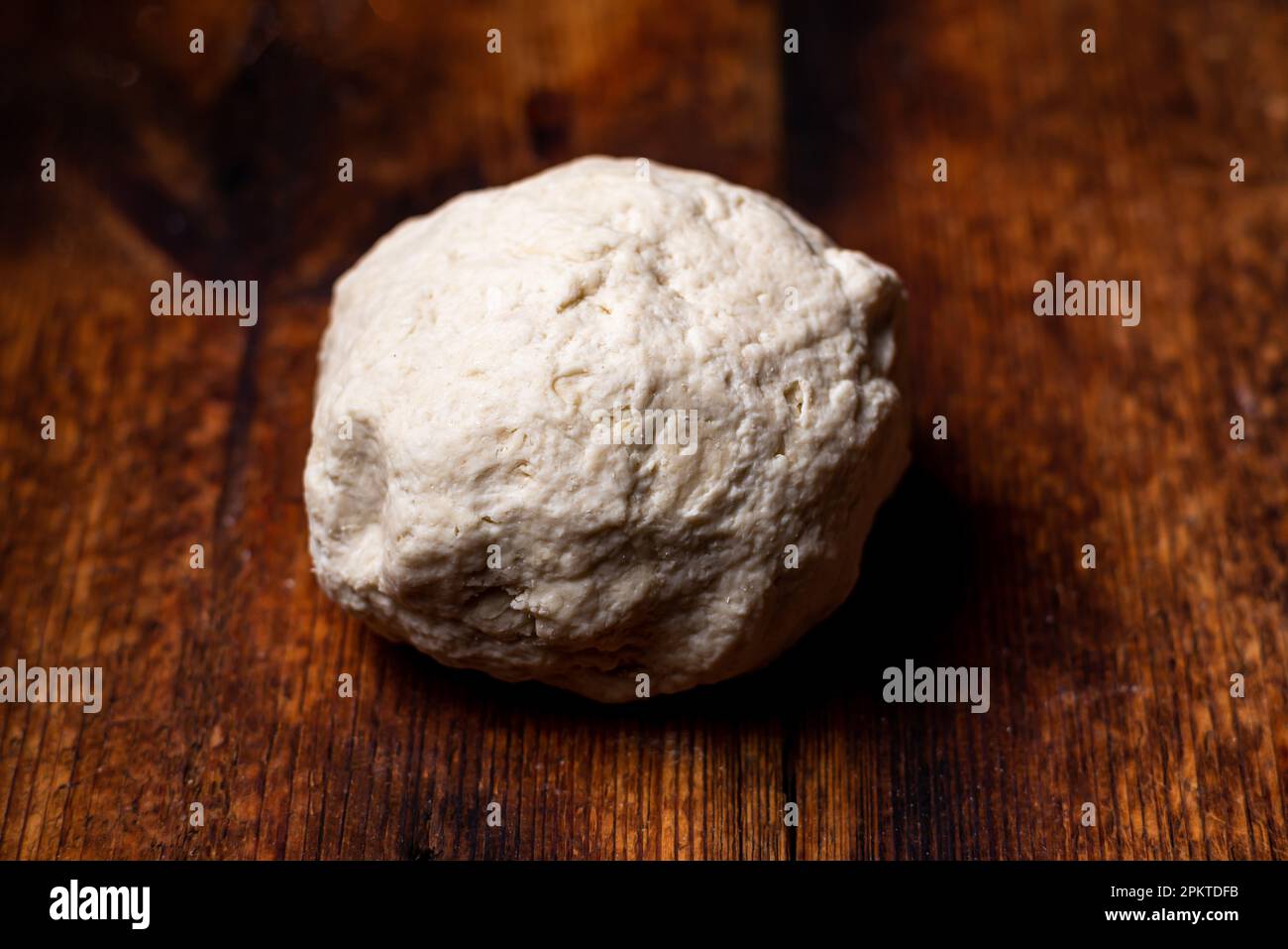 Teigkugel auf Holzfläche. Zubereitung von Schüttelteig für die Brotherstellung, Basis für Pizza, Baguettes Stockfoto