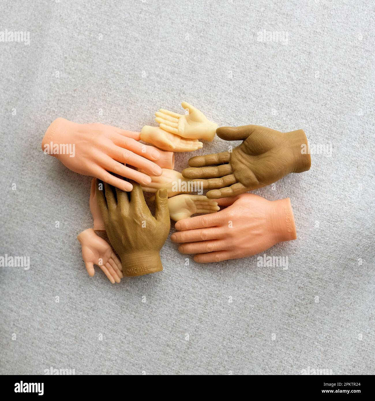 Plastikspielzeug Finger Hände in verschiedenen Hauttönen; Hilfe, Hilfe, Harmonie, Diversitätskonzept; Kleine Fingerhände. Stockfoto