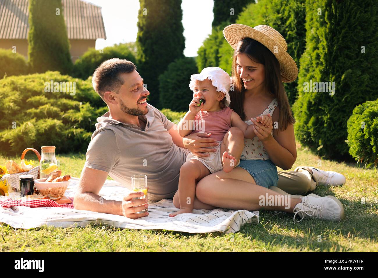 Glückliche Familie mit Picknick im Garten an sonnigen Tagen Stockfoto