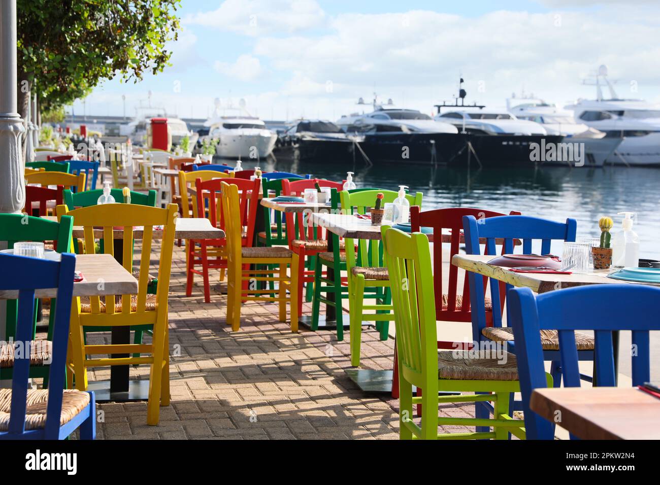 Wunderschöner Blick auf das Café im Freien mit bunten Holzstühlen in der Nähe des Piers Stockfoto