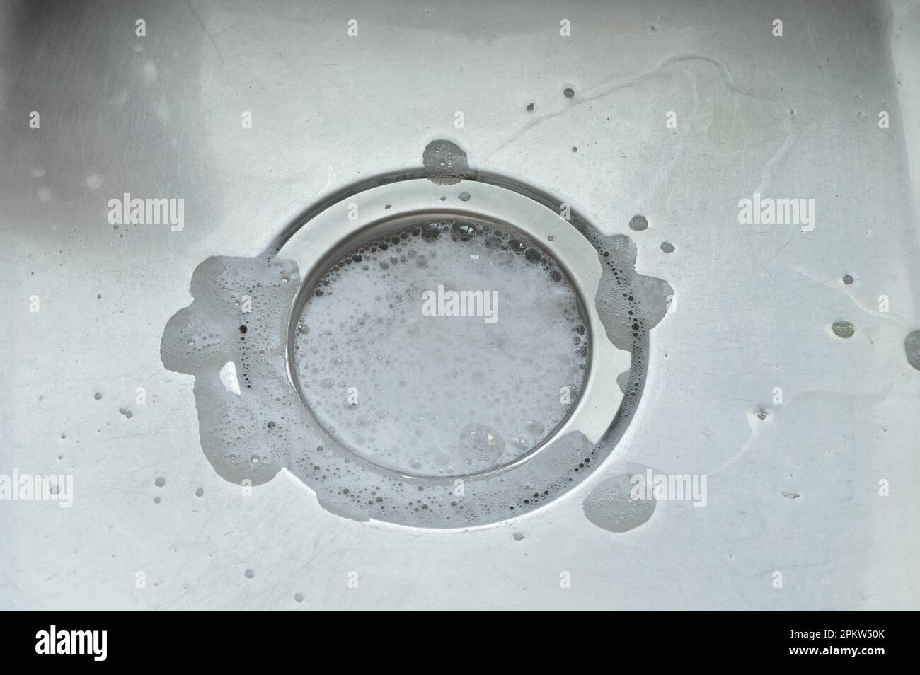 Wasser mit Seifenschaum im Stahlwaschbecken läuft ab Stockfoto