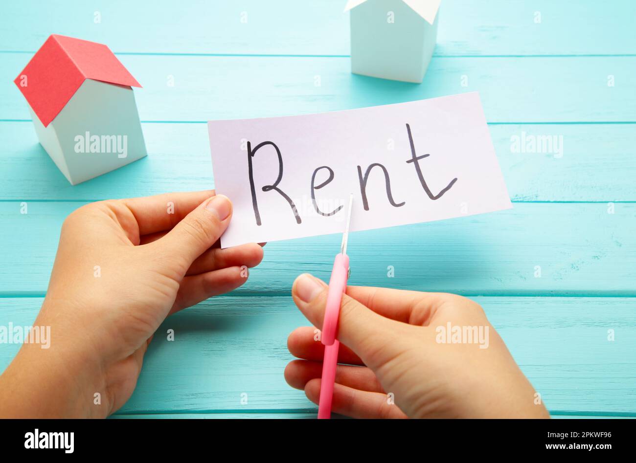 Das Wort "Rent" steht auf Papier und wird mit einer Schere in zwei Hälften geschnitten. Draufsicht Stockfoto