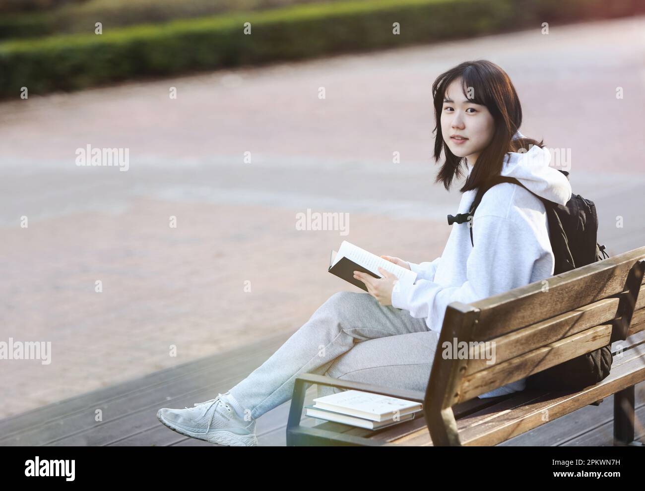 Konzept für Schüler und Studenten mit Rucksack, der auf einer Parkbank sitzt und liest und studiert Stockfoto