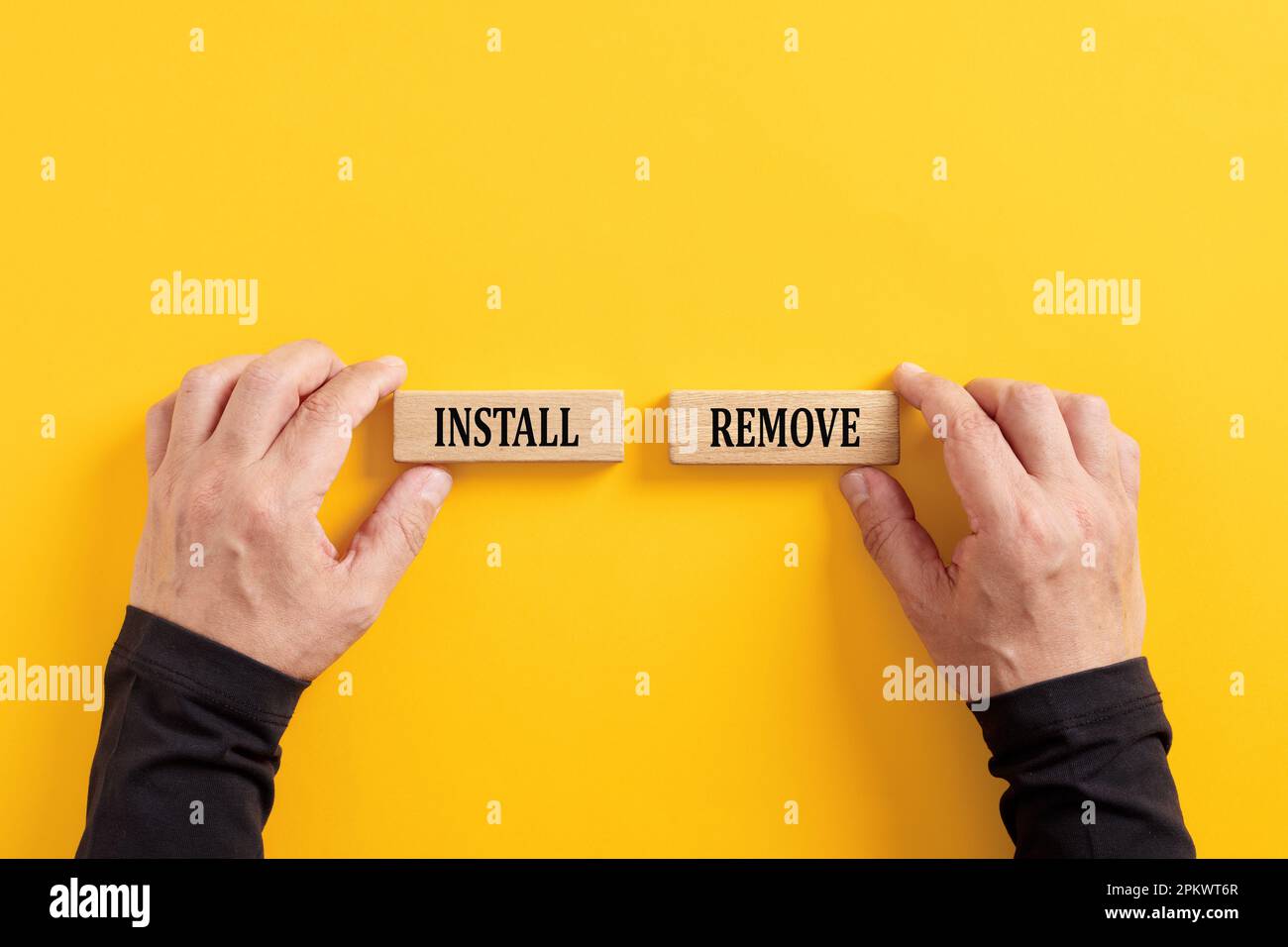 Entscheidung, eine mobile Anwendung oder Programmsoftware zu installieren oder zu entfernen. Hände halten Holzblöcke mit den Wörtern Einbauen und Entfernen. Stockfoto