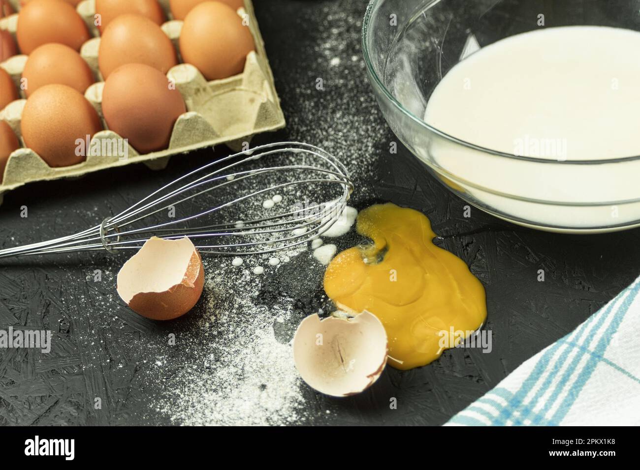 Ein zerbrochenes Ei auf dem Tisch, ein Chaos am Arbeitsplatz des Kochs. Hühnerei fiel auf den Tisch. Platz für Text Stockfoto