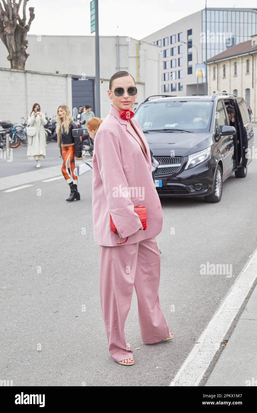 MAILAND, ITALIEN - 23. FEBRUAR 2023: Frau mit pinkfarbener Jacke und Hose und roter Blumenkette vor der Modenschau Prada, Mailand Fashion Week Street sty Stockfoto