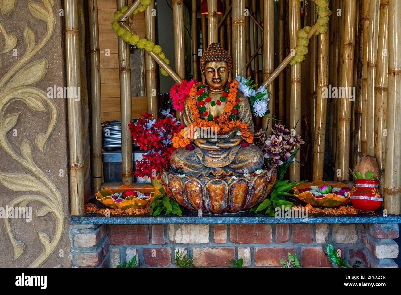 Bronze-buddha-Statue in Meditation mit Blumendekorationen für die Festivalzeremonie. Hochwertiges Foto Stockfoto