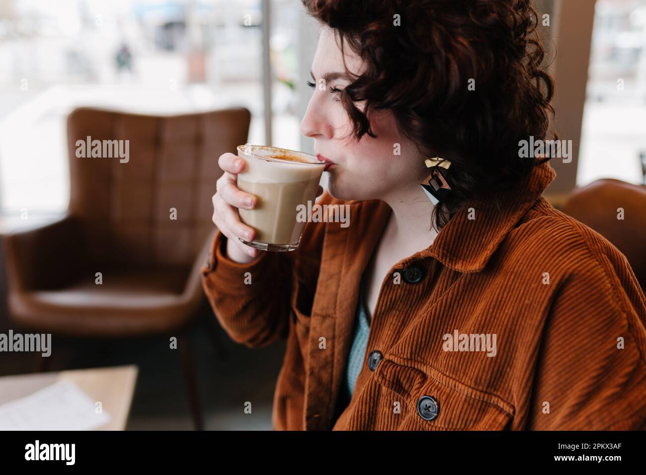 Profilansicht einer schönen Frau, die einen Latte trinkt Stockfoto