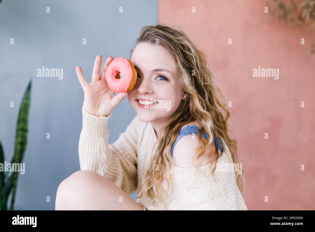 Porträt einer lächelnden, schönen Frau, die durch ein Donut-Loch schaut Stockfoto
