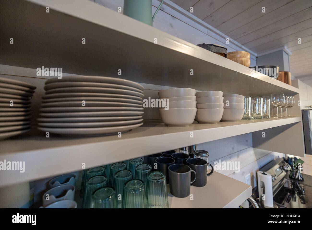 Schüsseln, Teller und Tassen auf offenen Regalen in einer Küche Stockfoto