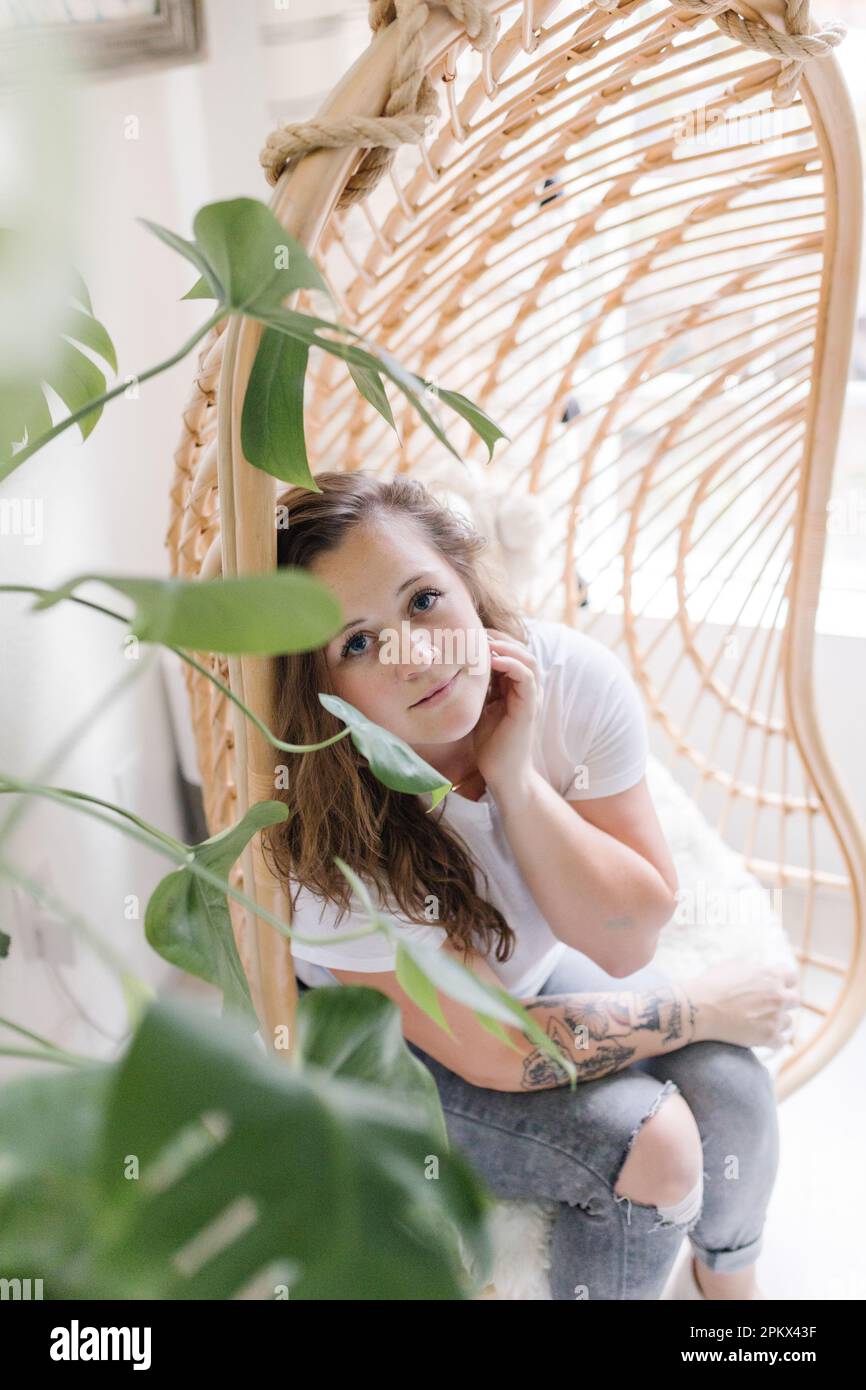 Porträt einer aufmerksamen, schönen Frau, die durch Pflanzen schaut Stockfoto