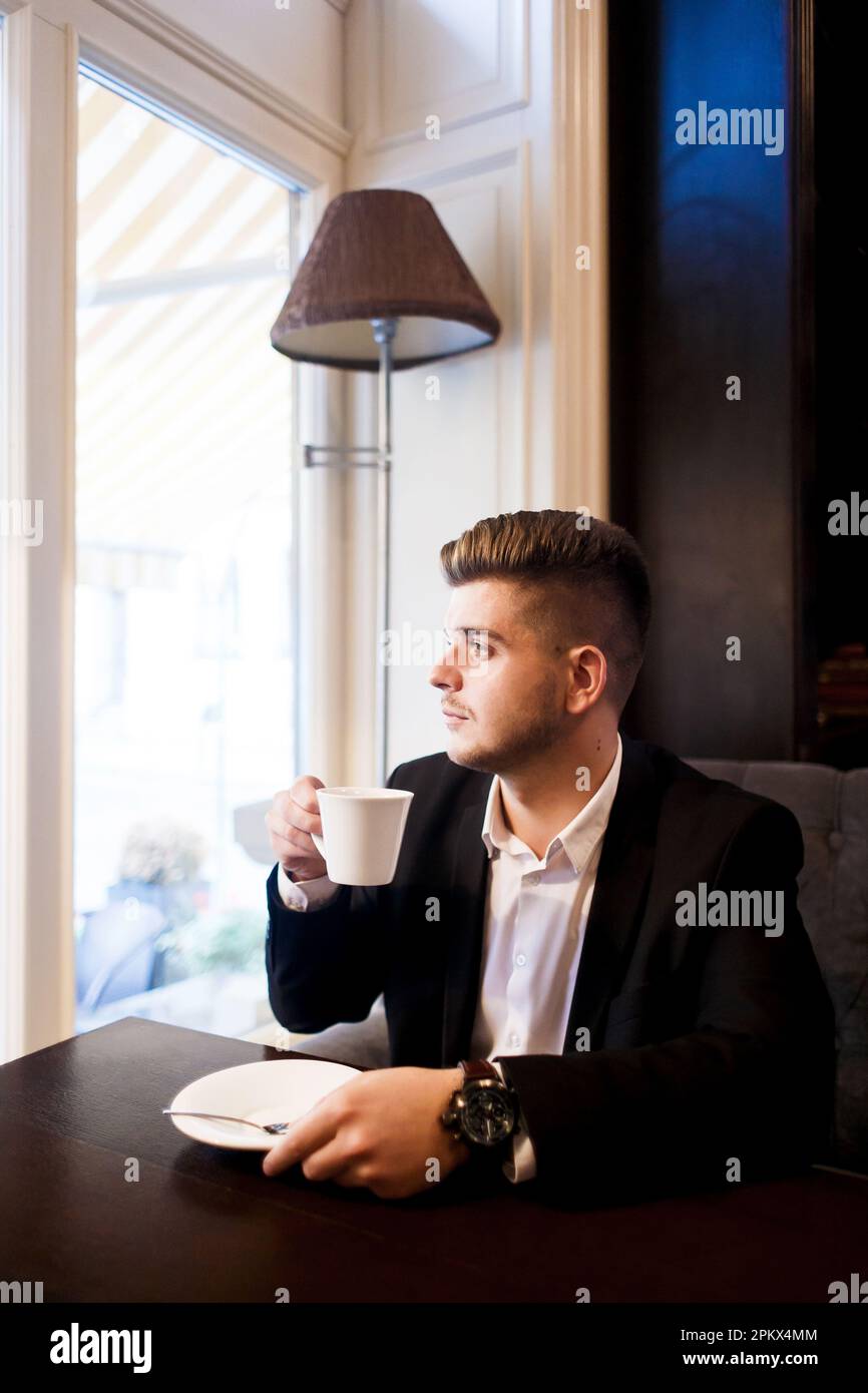 Ein junger Mann im Anzug trinkt Kaffee bei einem Geschäftstreffen Stockfoto