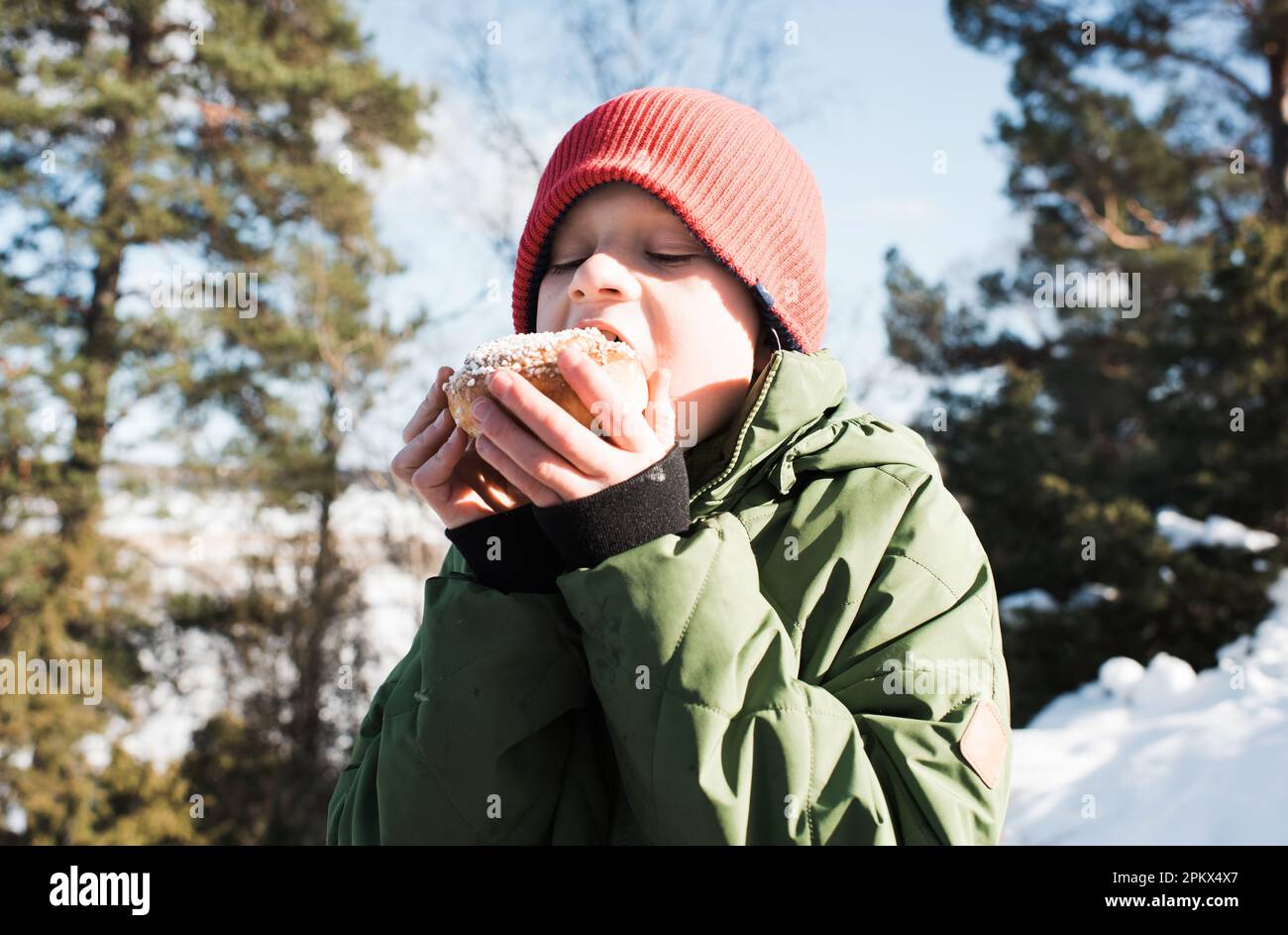 Ein Junge isst einen Kanelbular, während er draußen in Schweden ist Stockfoto