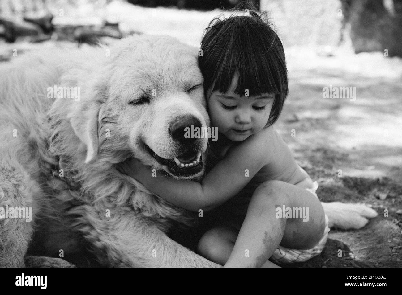 Süßes Baby kuschelt liebevoll mit dem alten Hund Stockfoto