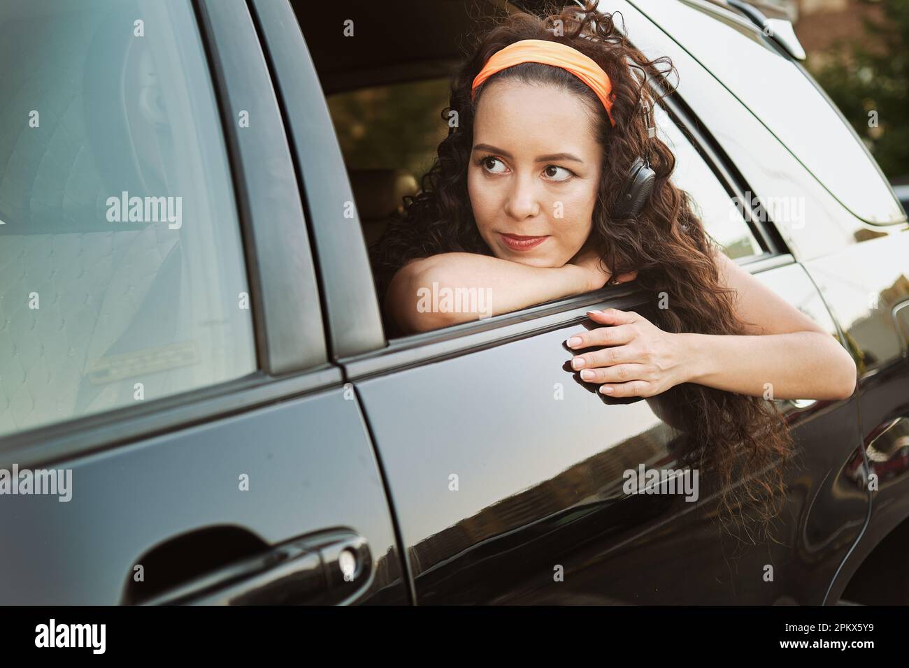 Das Mädchen schaut aus dem Autofenster und hört Musik Stockfoto