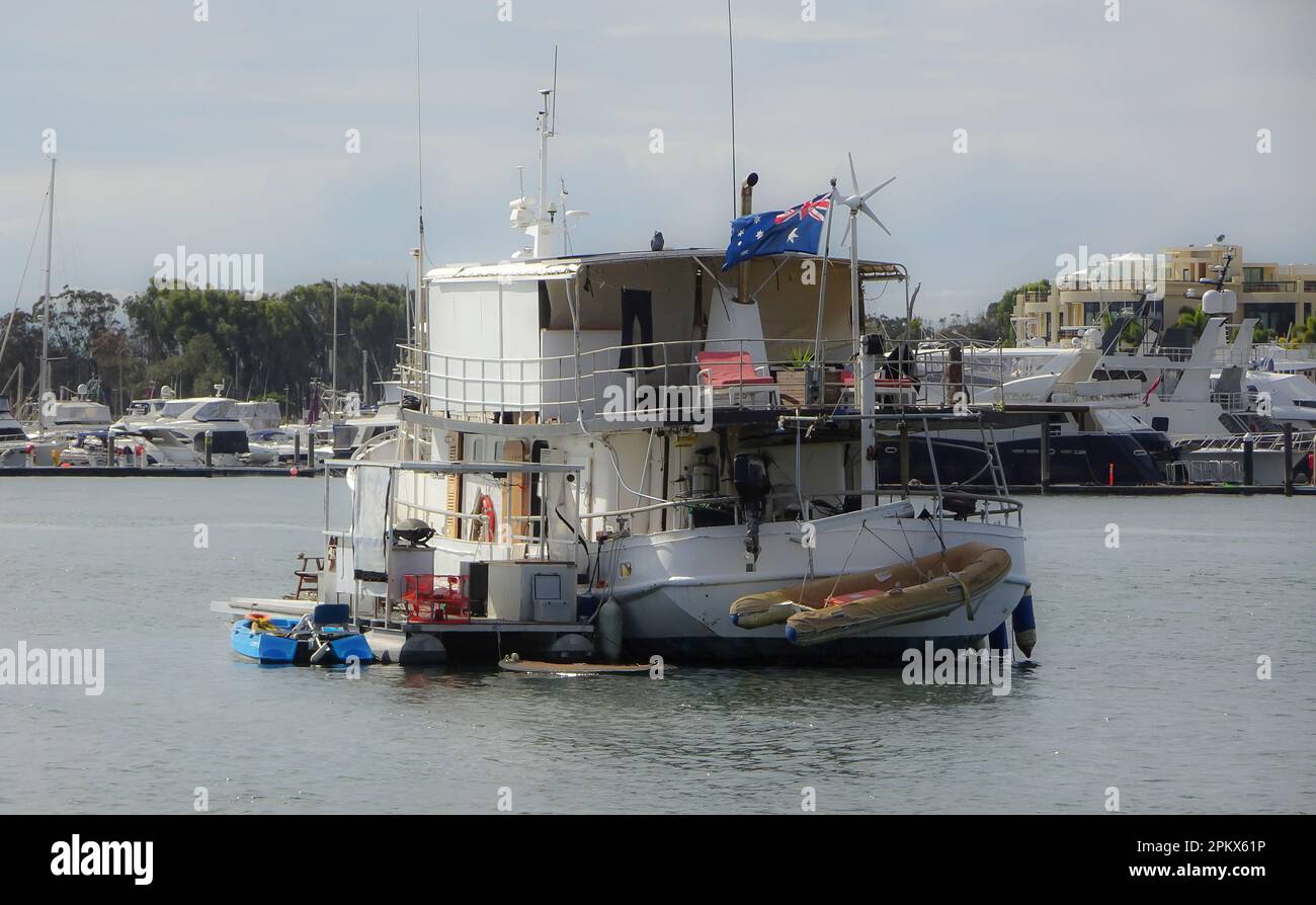 Individuell gestaltetes Hausboot auf dem Broadwater in Southport, Gold Coast, Australien. Im Gegensatz zu Luxusyachten und Hotels im Hintergrund. Stockfoto