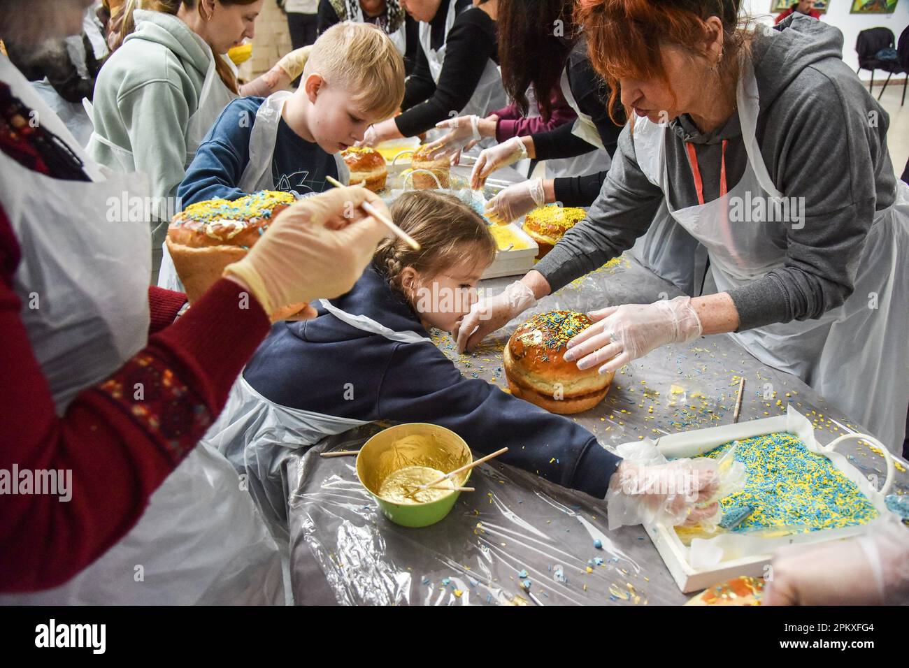 Ein kleines Mädchen dekoriert traditionelle ukrainische Osterkuchen, um einen Rekord für die Herstellung des Trident der Ukraine aus tausend Osterkuchen zu setzen. In Lemberg wurde ein neuer ukrainischer Rekord aufgestellt - in 25 Minuten und 17 Sekunden schmückten die Menschen 1.000 Osterkuchen und legten sie in Form eines Dreizacks aus. Dies ist der größte ukrainische Dreizack, der je aus Osterkuchen hergestellt wurde. Alle Osterkuchen werden verkauft, und die Erlöse werden verwendet, um Drohnen für die ukrainische Armee zu kaufen. Stockfoto