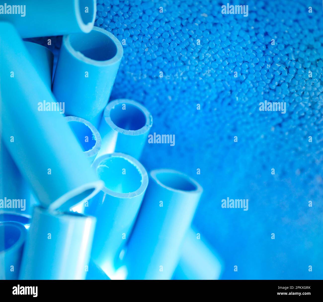 Blaue Rohre und Kunststoff-Polymer-Pellets als Rohmaterial für die Produktion von blauen pvc-Rohren. Industrielles Kunststoffharz. Chemisches Polymergranulat. Thermoplast. Stockfoto