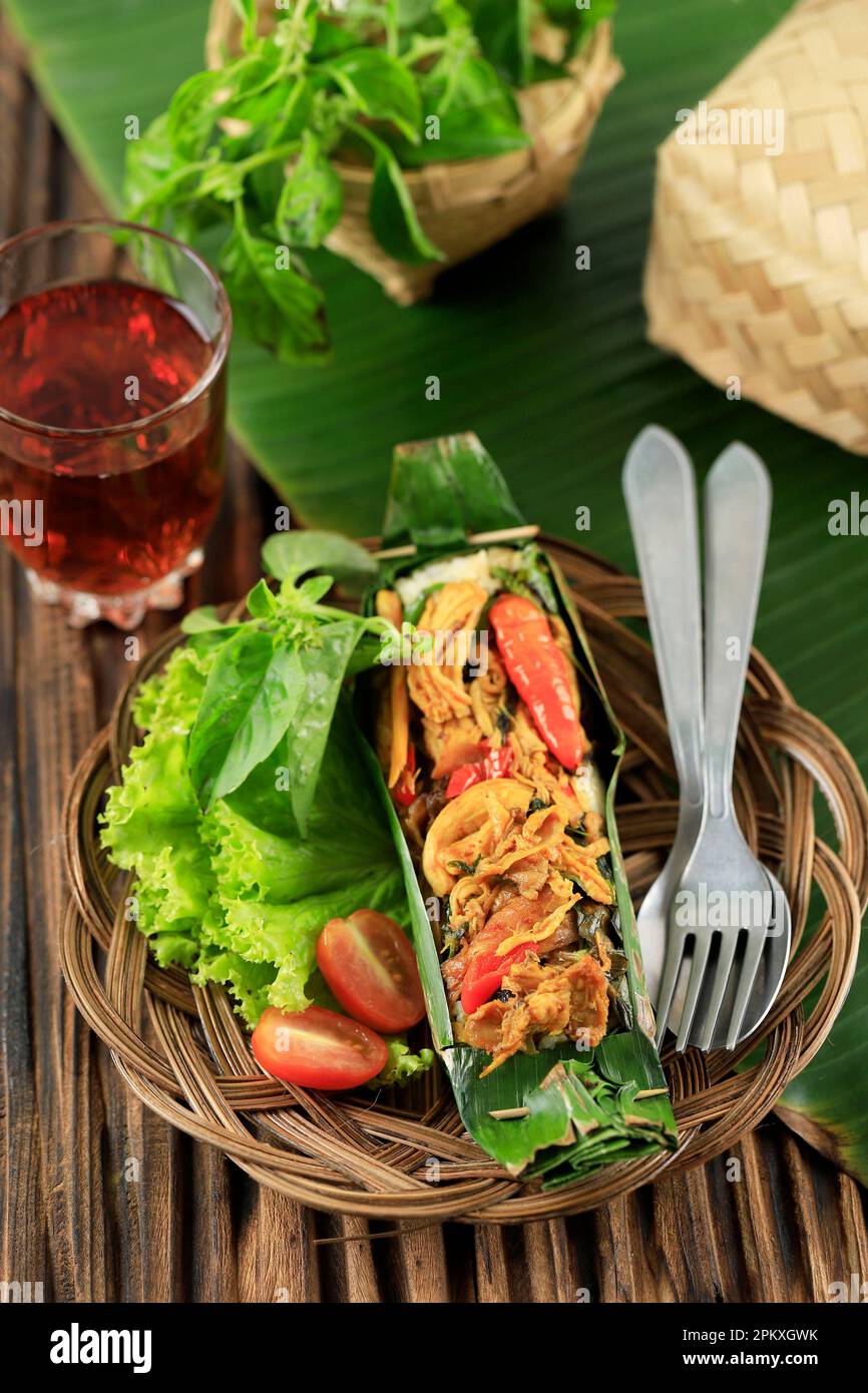 Nasi Bakar Ayam Suwir Kemangi, gedünsteter Reis mit gebratenem, würzigem Hähnchen und süßem Basilikumblatt, Umhang mit Bananenblatt und gegrilltem Stockfoto