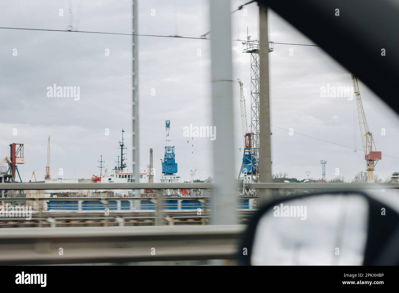 Blick aus dem Fenster eines fahrenden Autos auf den Metallkränen im Transporthafen. Stockfoto