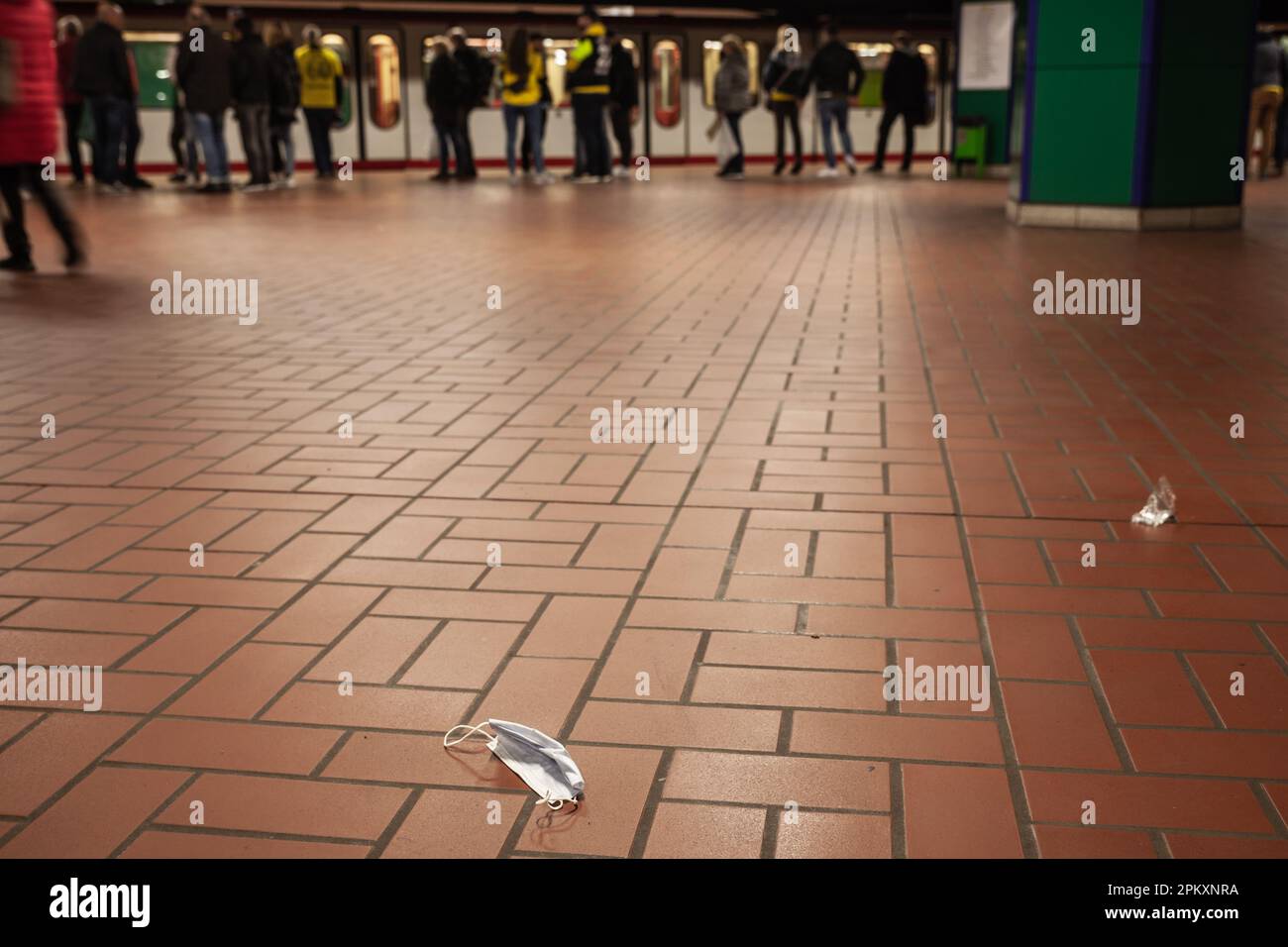 Bild einer alten Einweg-Gesichtsmaske auf dem Boden, in einer Straßenbahn und U-Bahn öffentlichen Verkehrsstation in Dortmund, Gerany, während des Coronavirus cr Stockfoto