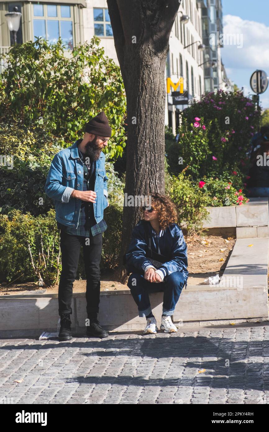 Stilvoller urbaner dialog: Zwei Hipster unterhalten sich in den lebhaften Straßen von Paris, Frankreich Stockfoto