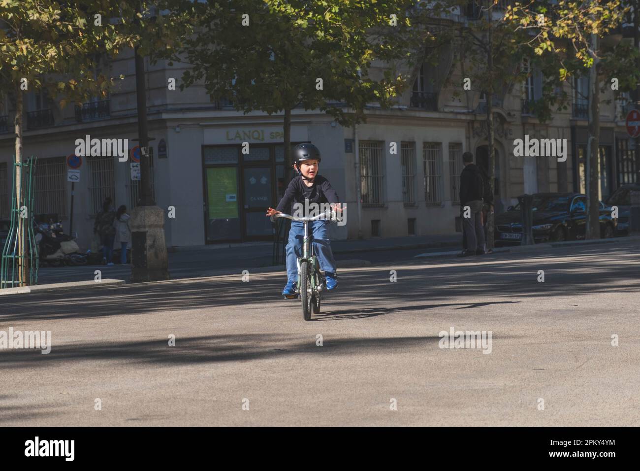 Junge mit Helm genießt Fahrradabenteuer in den Straßen von Paris Stockfoto