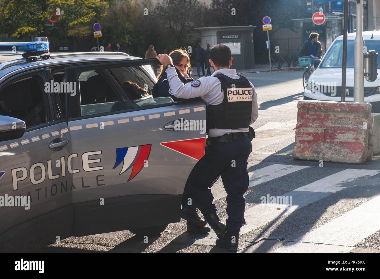Männliche und weibliche Polizisten, die sich neben dem Polizeiauto in Paris unterhalten Stockfoto