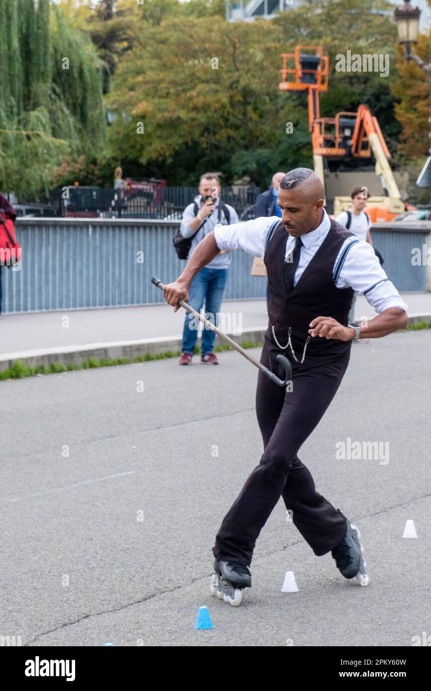 Black man in 1940er-Kleidung Rollerblading mit Schnurrbart auf einer Pariser Brücke, faszinierende Zuschauer Stockfoto