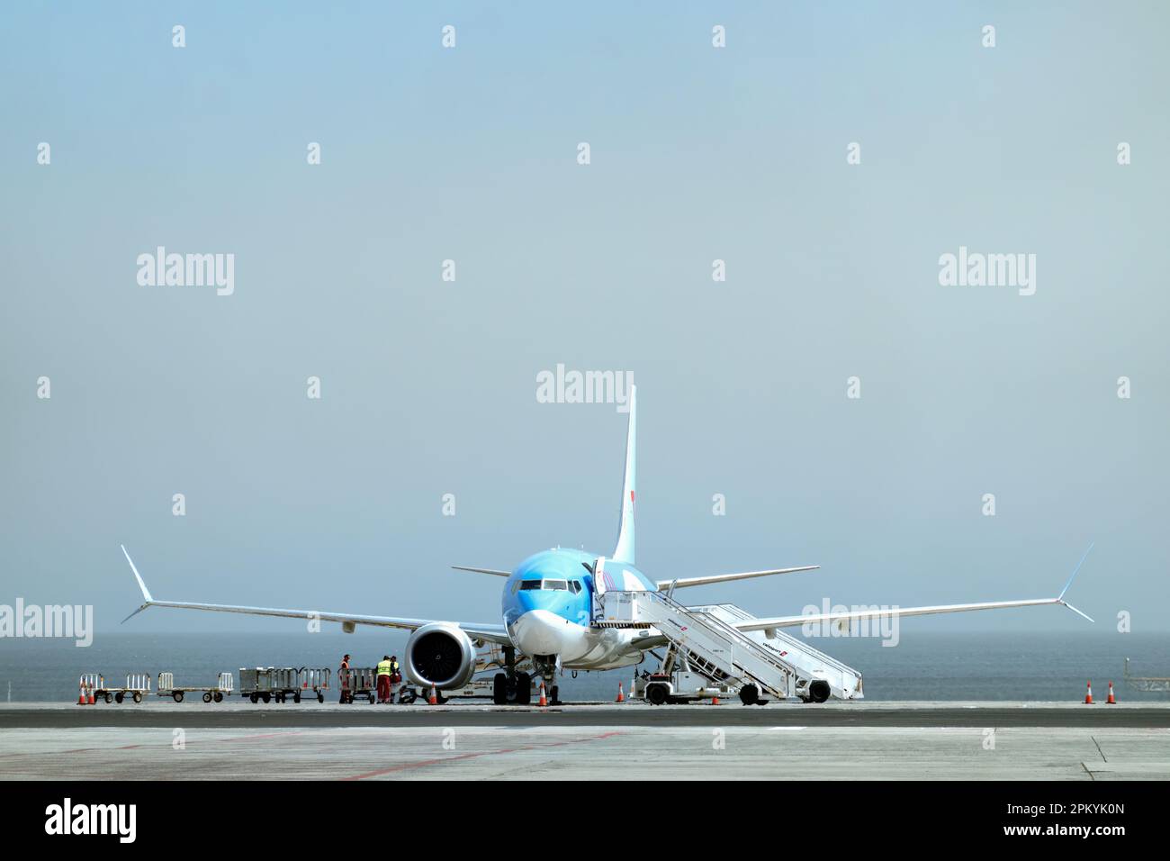 Ein TUI-Flugzeug auf dem Vorfeld eines verkehrsreichen Flughafens. Die Serviceteams bereiten das Flugzeug für den Flug vor und laden das Gepäck der Passagiere Stockfoto