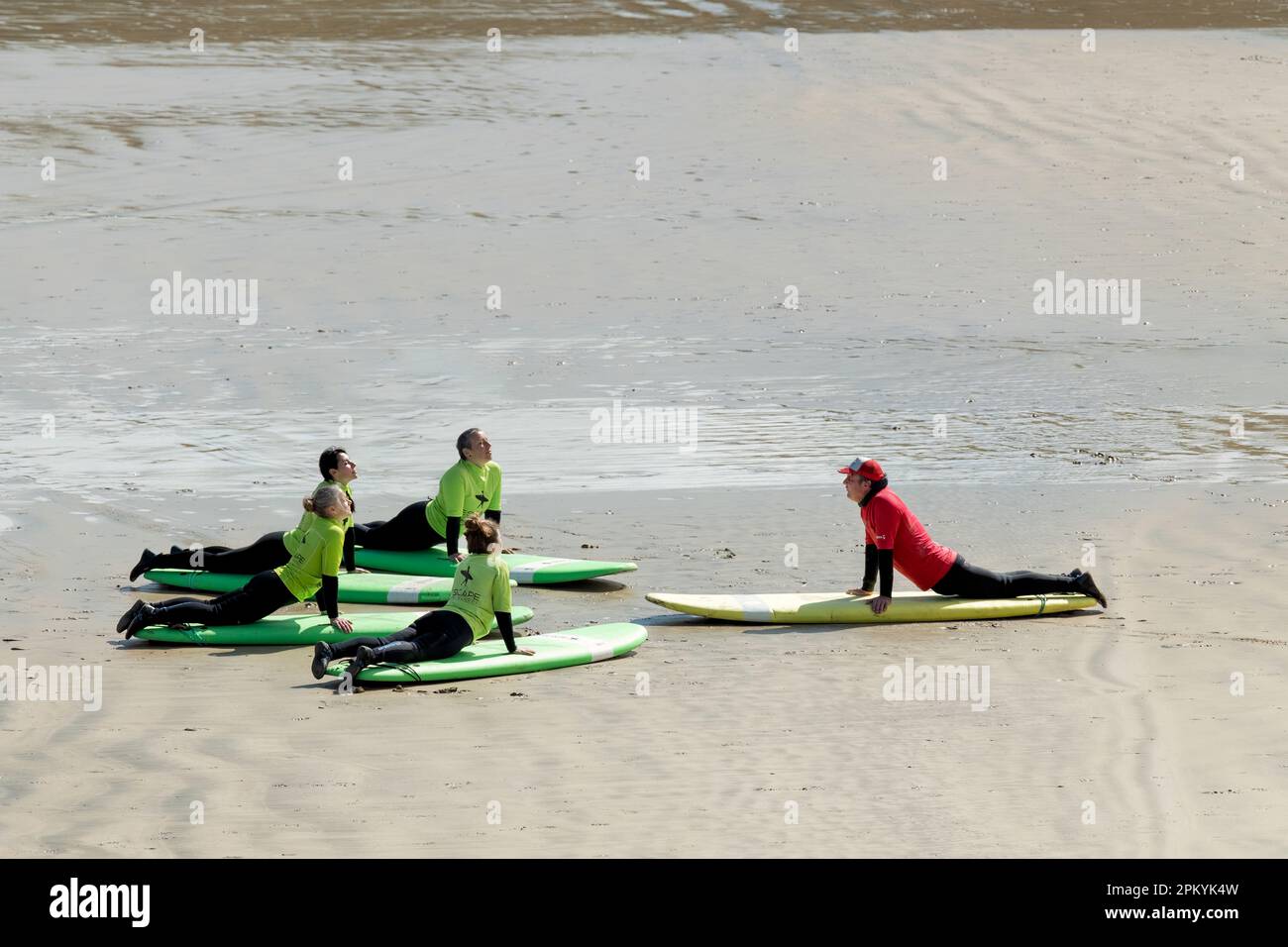 Cornwall: Eine Gruppe von Schülerinnen, die in einer Surfschule von einer Lehrerin einige grundlegende Manöver lehrt. Die Schüler liegen auf Surfbrettern Stockfoto