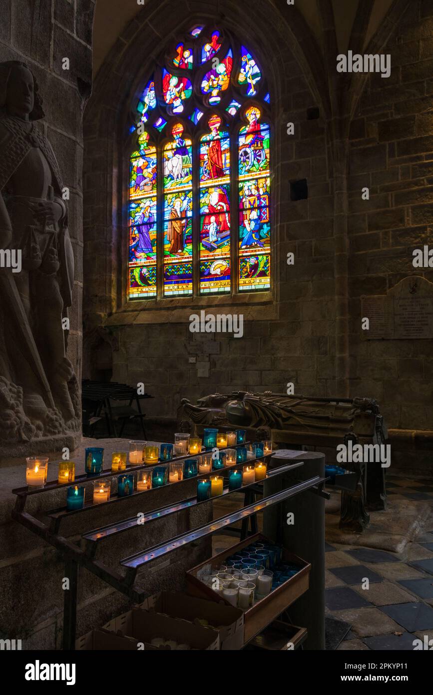 Kerzen und Buntglasfenster in der St.-Ronan-Kirche, Locronan, Bretagne, Frankreich Stockfoto