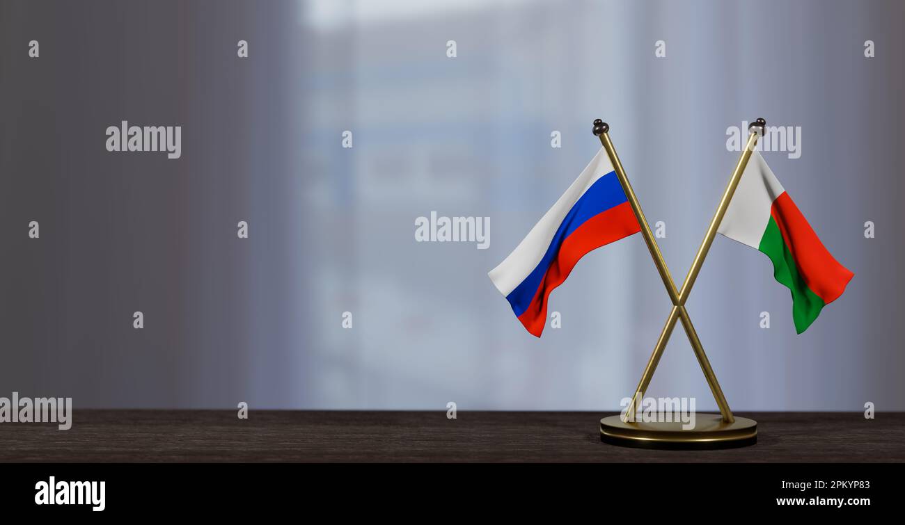 Russische und madagassische Flaggen auf dem Tisch. Verhandlungen zwischen Madagaskar und Russland. Auf wenig unscharfem Hintergrund. 3D Arbeit und 3D Bild Stockfoto