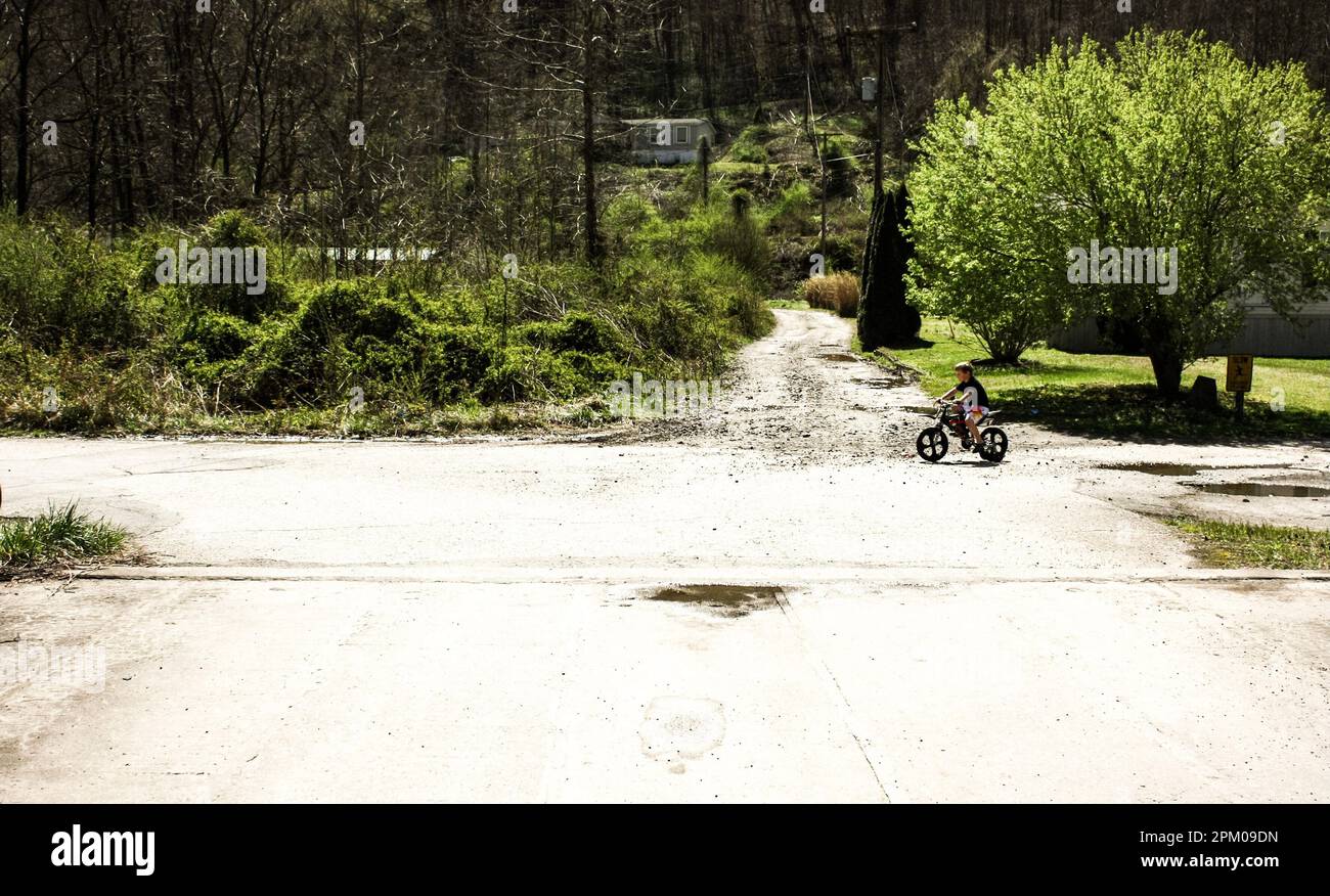 Ein kleiner Junge, der an einem sonnigen Tag im Frühling auf einer Landstraße im Südwesten von virginia, usa, mit dem Fahrrad fährt Stockfoto