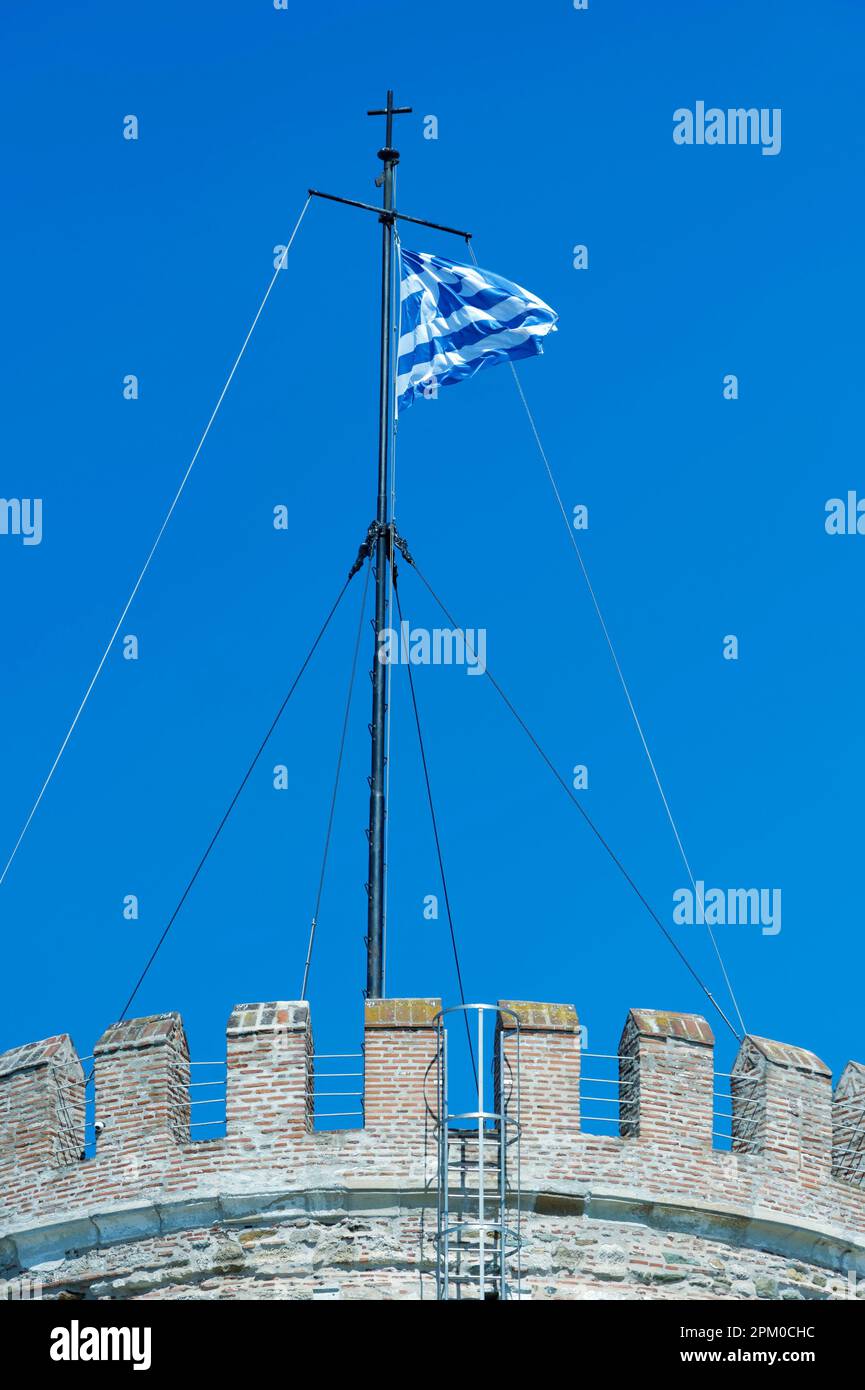 Foto der griechischen Nationalflagge, die im Wind auf dem Weißen Turm von Thessaloniki, Griechenland, weht Stockfoto