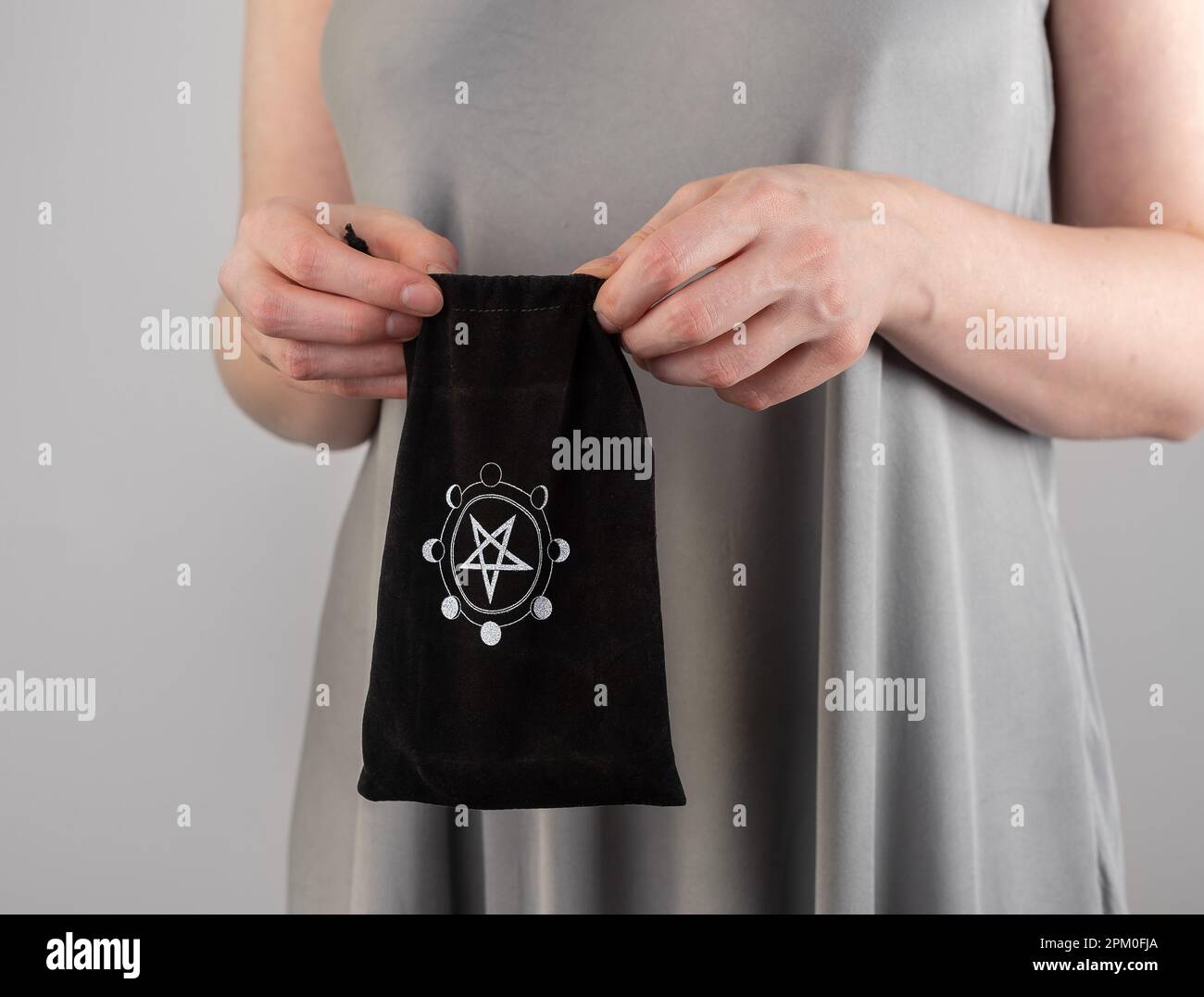 Lodz, Polen, 07 2023. April, Hände mit schwarzer mystischer Tasche mit esoterischem Sternsymbol. Stockfoto