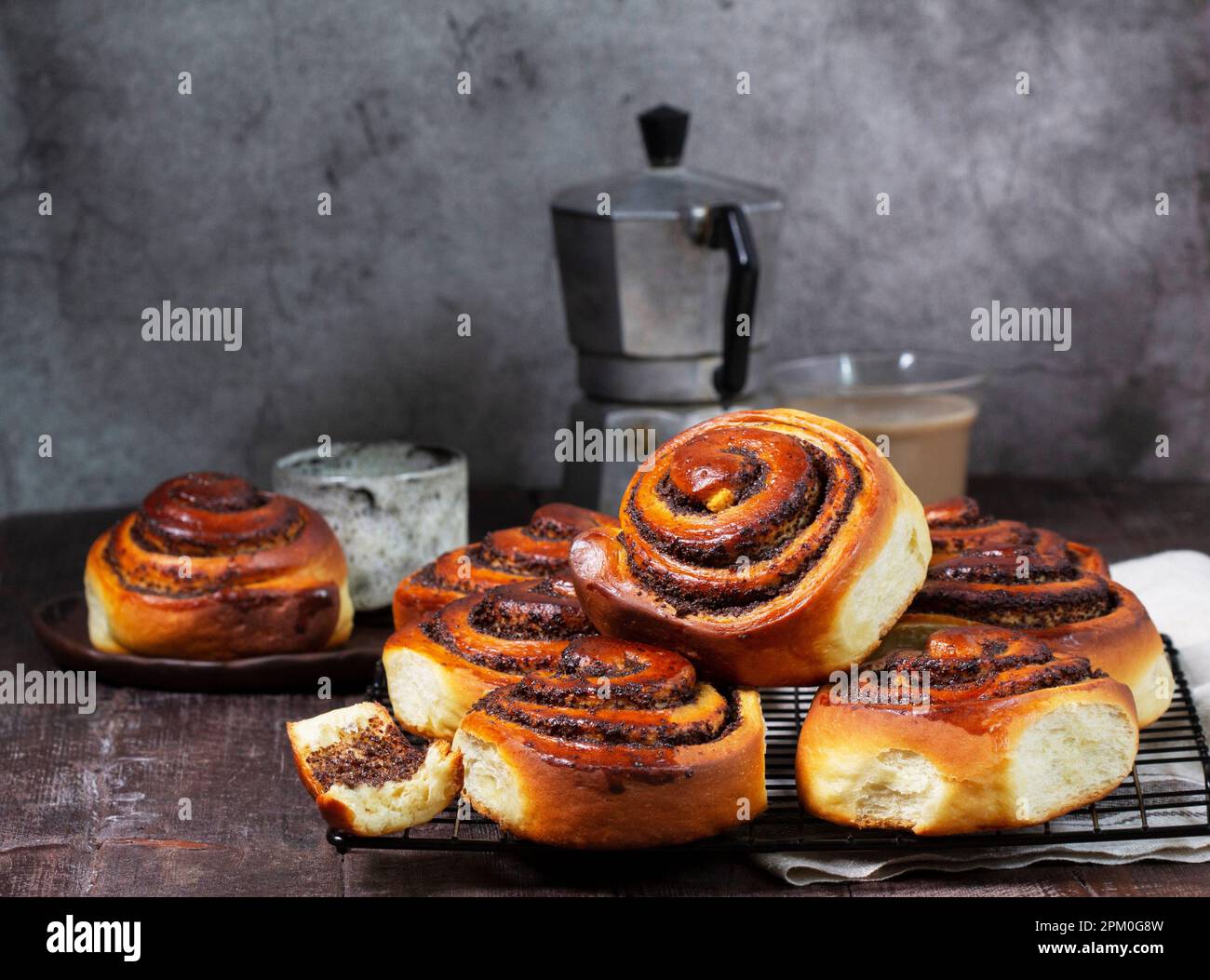Hefeteig mit Zimt mit Mohnsamen, Rosinen und kandierten Früchten, serviert mit Kaffee. Rustikaler Stil. Stockfoto