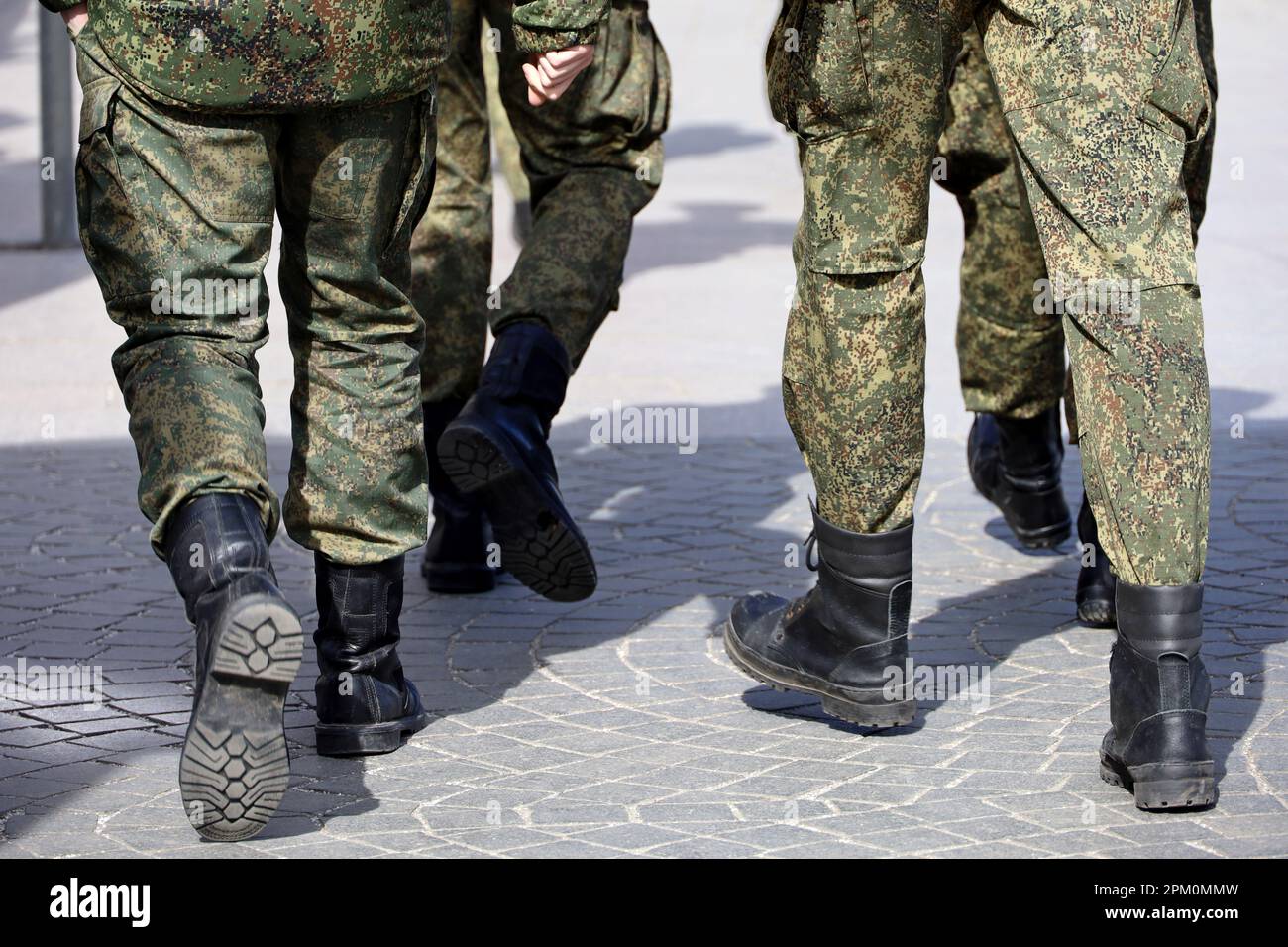 Beine von Soldaten der Streitkräfte in Tarnung, Männer in Stiefeln, die die Straße entlang laufen Stockfoto