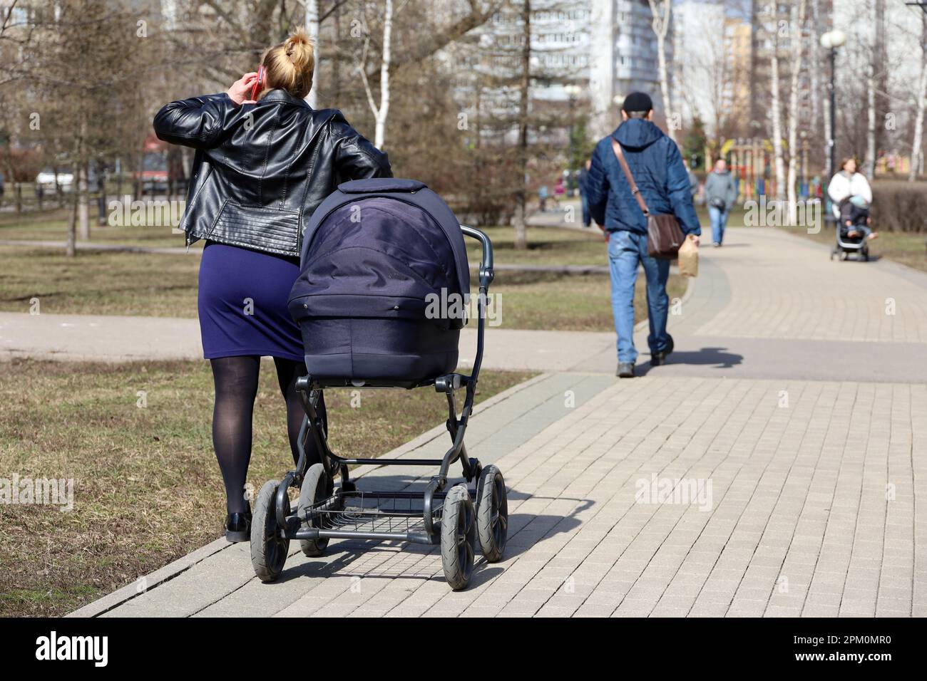 Eine Frau, die mit einem Kinderwagen auf dem Bürgersteig telefoniert. Mutter mit Kind, Freizeit im Spring Park Stockfoto