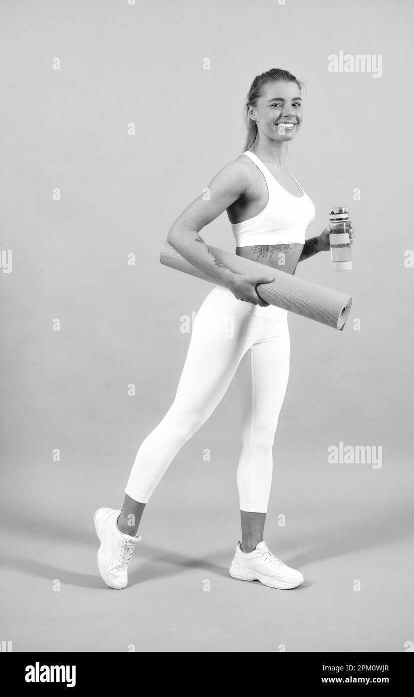 Sportliche Frau mit Yogamatte. Junge Fitness-Läuferin, die sich vor dem Laufen die Beine streckt. Sport und gesunder Lebensstil. Stockfoto