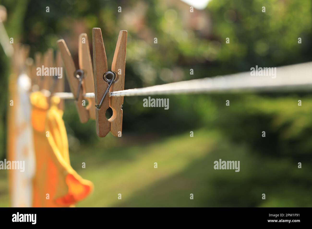 Saubere Kleidung trocknet an sonnigen Tagen im Freien, konzentrieren Sie sich auf die Wäscheleine mit Holzkleidern Stockfoto