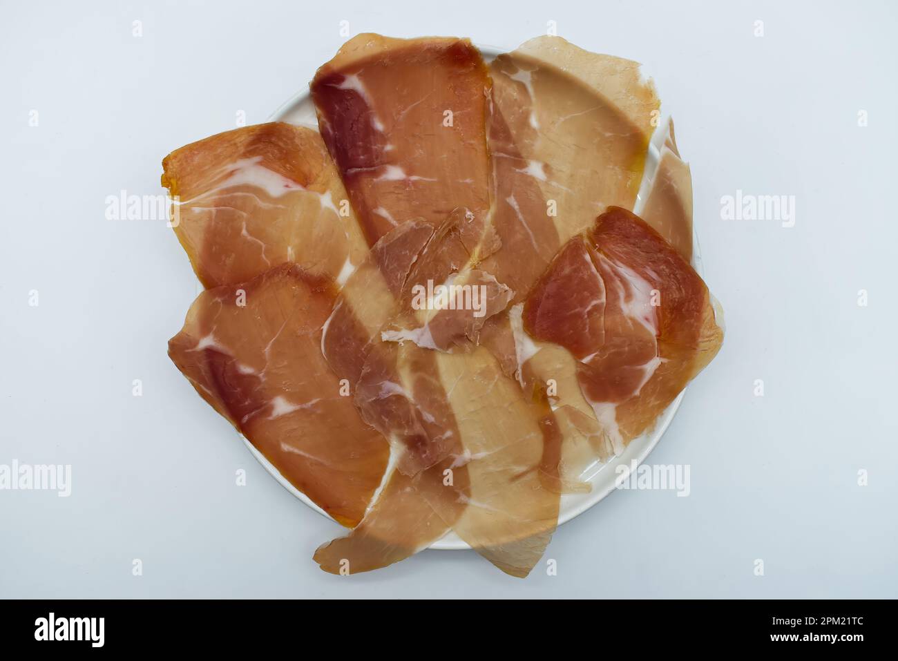 Scheiben von italienischem Prosciutto di parma, italienischem Schinken, in einem weißen Gericht isoliert auf Weiß. Draufsicht Stockfoto