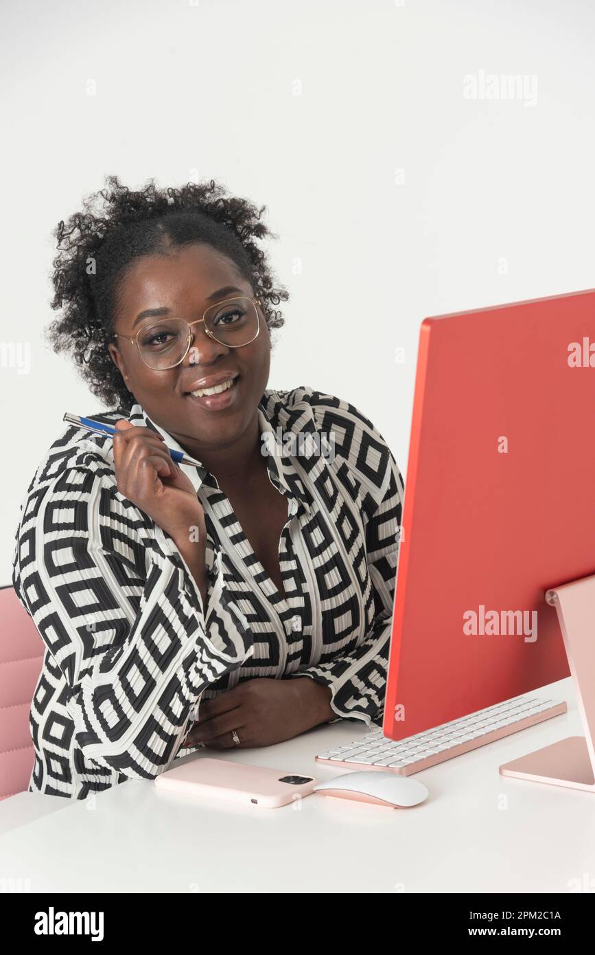 England, Großbritannien. 2022. Glückliche lächelnde Frau, die an einem Desktop-Computer arbeitet und in die Kamera schaut. Stockfoto